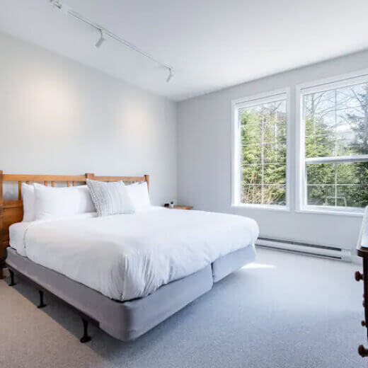 Bright master bedroom with a king-size bed and large windows.