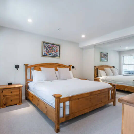 Elegant king-size bedroom with wooden frame and mirrored wall.